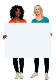 Full length portrait of two young women holding blank billboard