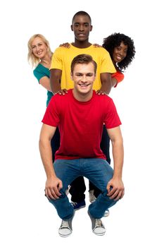 Young people standing behind semi seated guy. African guy resting hands on guy in front