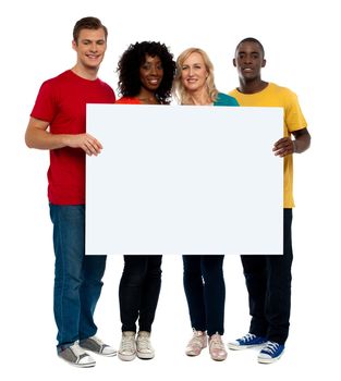 Team of young people holding whiteboard and presenting it to camera