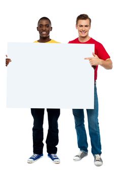 Young man pointing at white ad board while other holding board