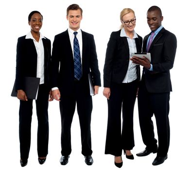 Corporate team of four posing with tablet pc. One team using tablet and other members facing camera