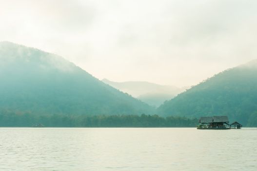 Hut on water in morning time with mountain and fog