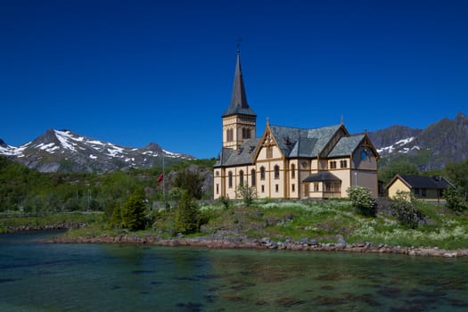 Picturesque Lofoten cathedral on Lofoten islands in Norway with snowy peaks in the background