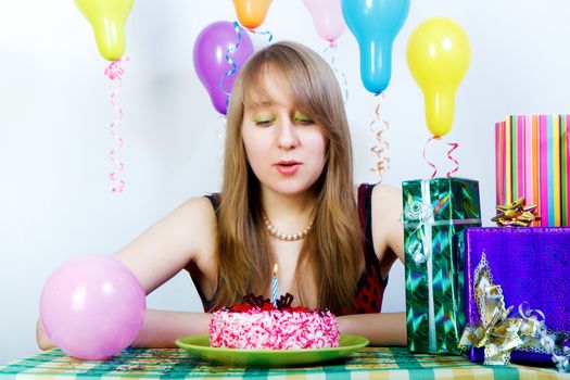 Birthday. An attractive young girl blows out the candle on the cake