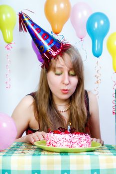 Birthday. An attractive young girl blows out the candle on the cake