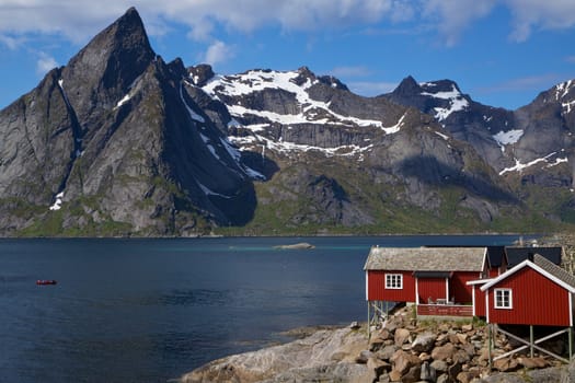 Picturesque red fishing hut on the coast of fjord on Lofoten islands in Norway