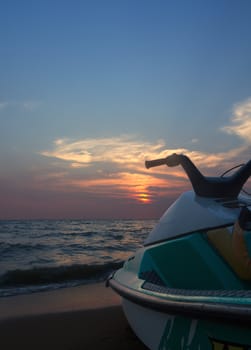 Jetski parked on a beach against blue sky and sunset