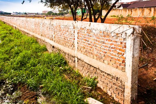 Fence placed a long brick wall. Village in Laos.