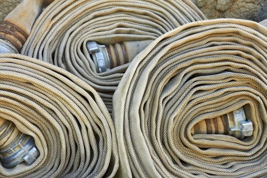 Old rolled fire hoses with nozzles close-up