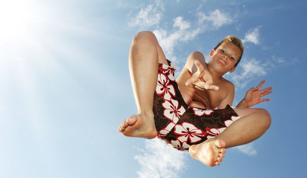 Little boy is jumping in front of the sky showing victory sign