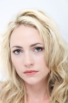Portrait of a wistful sad blonde woman with beautiful eyes on a white studio background 