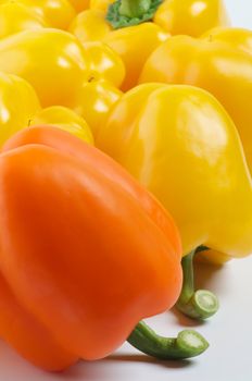 Yellow and Orange Bell Peppers with Fresh Tails close up on Yellow Bell Peppers background