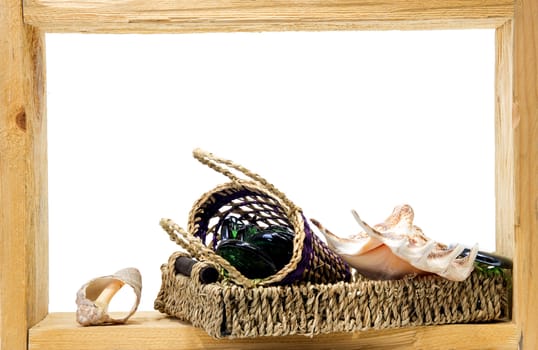 Wicker, green pieces of glass and sea shells inside rough wooden frame on white background