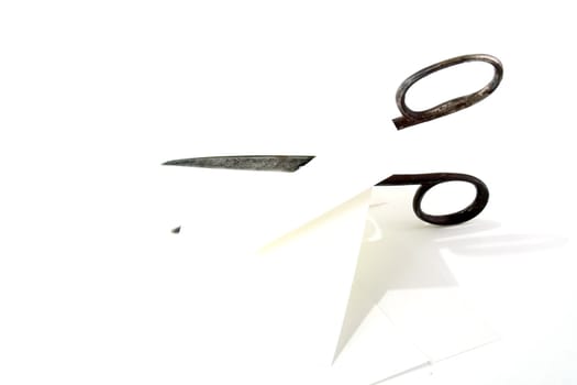 Old rusty steel scissors cut paper on white background