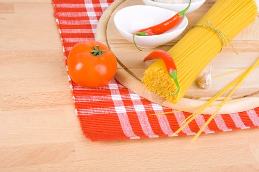 Golden raw dried Italian pasta with other ingredients on kitchen desk.