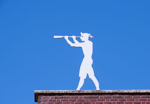 man on a roof looking with binoculars and a blue sky as background