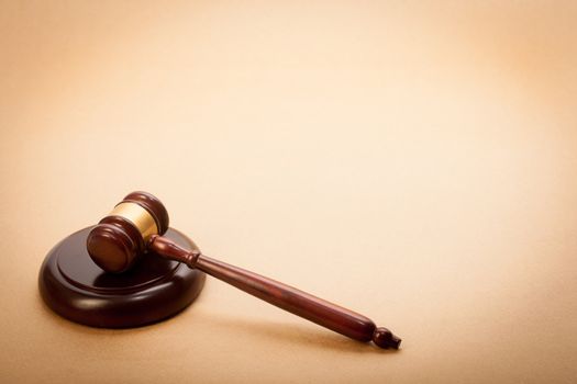 A wooden gavel and soundboard on a light brown background.