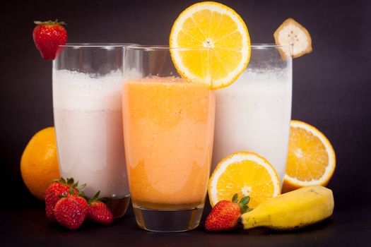 3 different juices and vitamins (strawberry, orange and banana) isolated on a black background.