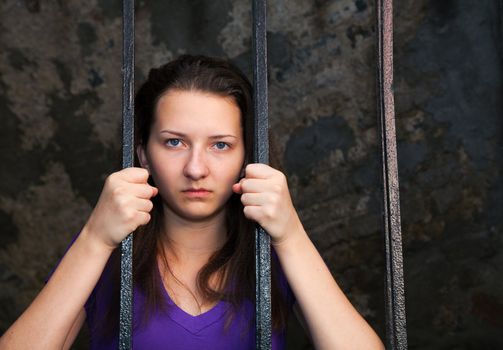 Young woman looking from behind the bars