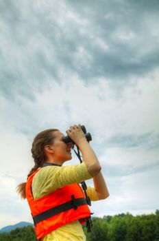 Young woman looking to sky through binoculars