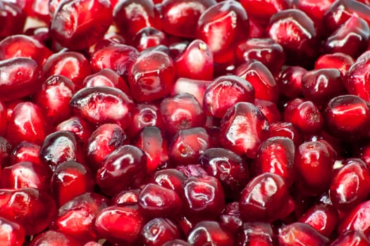 Extreme close up background of a red juicy ripe pomegranate fruit seeds 