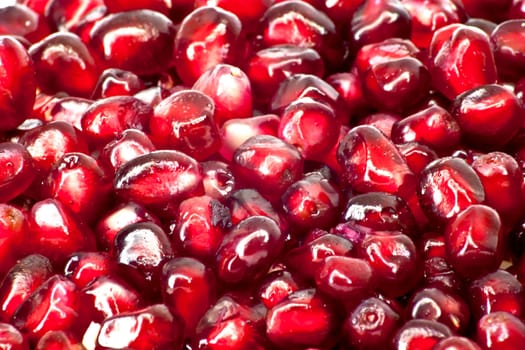 Extreme close up background of a red juicy ripe pomegranate fruit seeds 