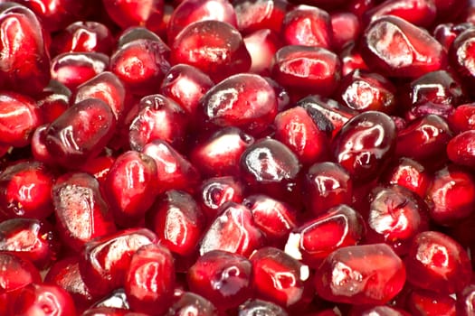 Extreme close up background of a red juicy ripe pomegranate fruit seeds 