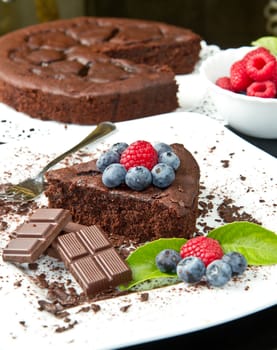 chocolate cake with fresh berry on white dish and black background