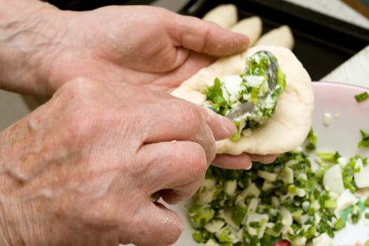 Hands of old woman making dough