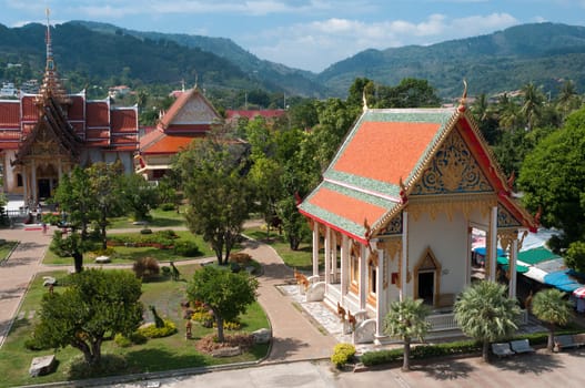 Buddhist temple complex with decorated lawns and mountains on background