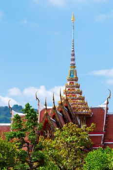 Buddhist temple roof with blue sky and green trees