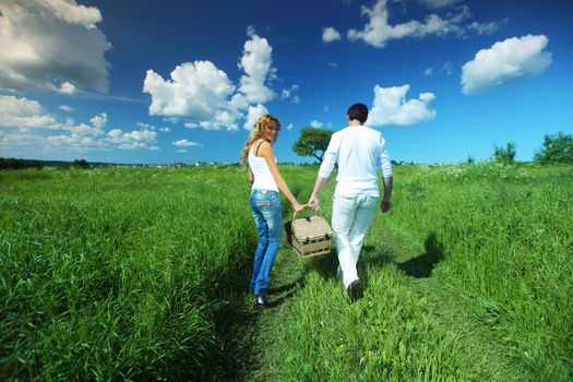 man and woman walk on picnic in green grass