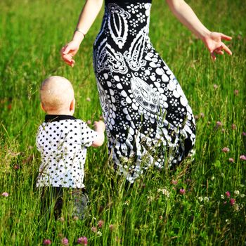 boy and mother hands in grass field