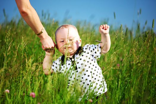 boy and mother hands in grass field