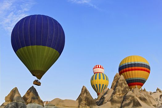 Hot air balloons captured coming over the limestone ridge near Goreme, Caapadocia, Turkey. The weathered mineral peaks which have eroded through evolution present a surreal backdrop to the striking colours of the passenger ladened aircraft.