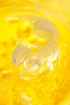 Whirlpool of yellow juice with lemon pieces flowing