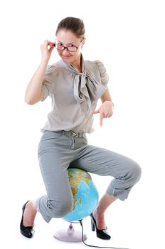 Beauty smiling woman in glasses is sitting on globe and showing on it by finger