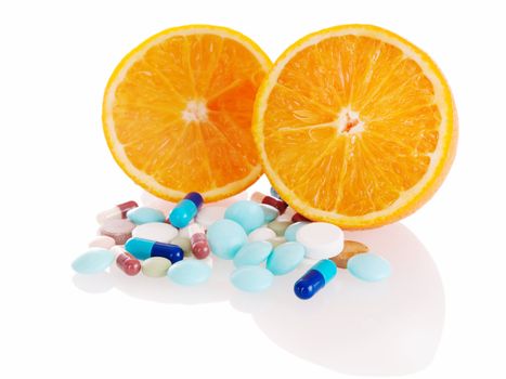 Concept of tasty madicine with heap of pills in front of two orange slices on white background. Focus on right orange.