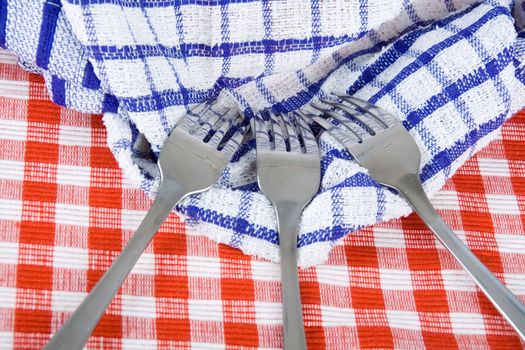 Shiny stainless steel forks on checkered fabric