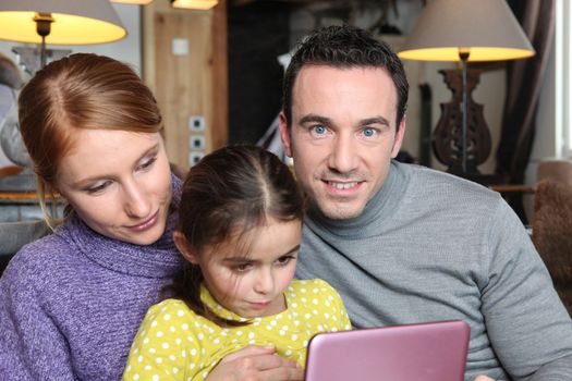 Family gathered on sofa with pink laptop