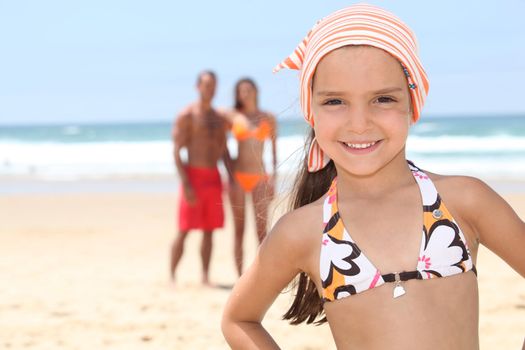 Little girl on the beach with her parents