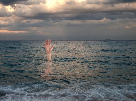 A hand hovering over the sea on a sunset with clouds, a symbol of a desperate plea for help.