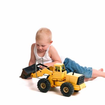 Little boy playing with a toy loader on the floor.