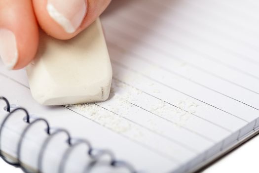 A woman's hand erasing text on a notepad, isolated on a white background.