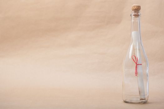 A message inside a glass bottle, isolated on a sand color background, in a studio shot.