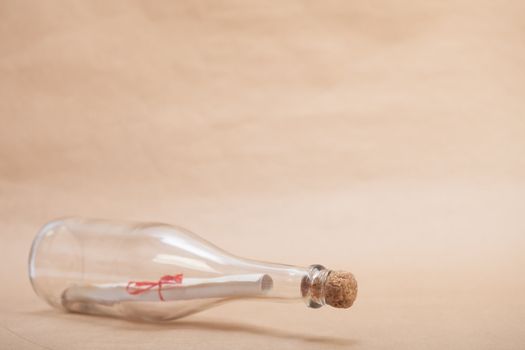 A message inside a glass bottle, isolated on a sand color background, in a studio shot.