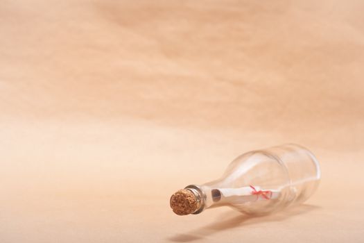 A message inside a glass bottle, isolated on a sand color background, in a studio shot.