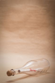 A message inside a glass bottle, isolated on a sand color background, in a studio shot.