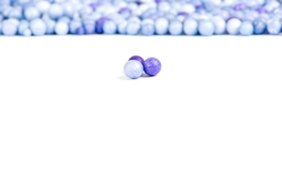 One blue and two violet little pearls isolated on background of other pearls.