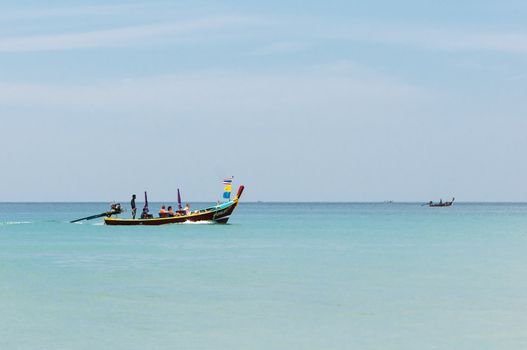 Karon, Phuket, Thailand - January 08, 2012: Traditional wooden Thai tourist boat with tourists on calm blue sea near Karon beach